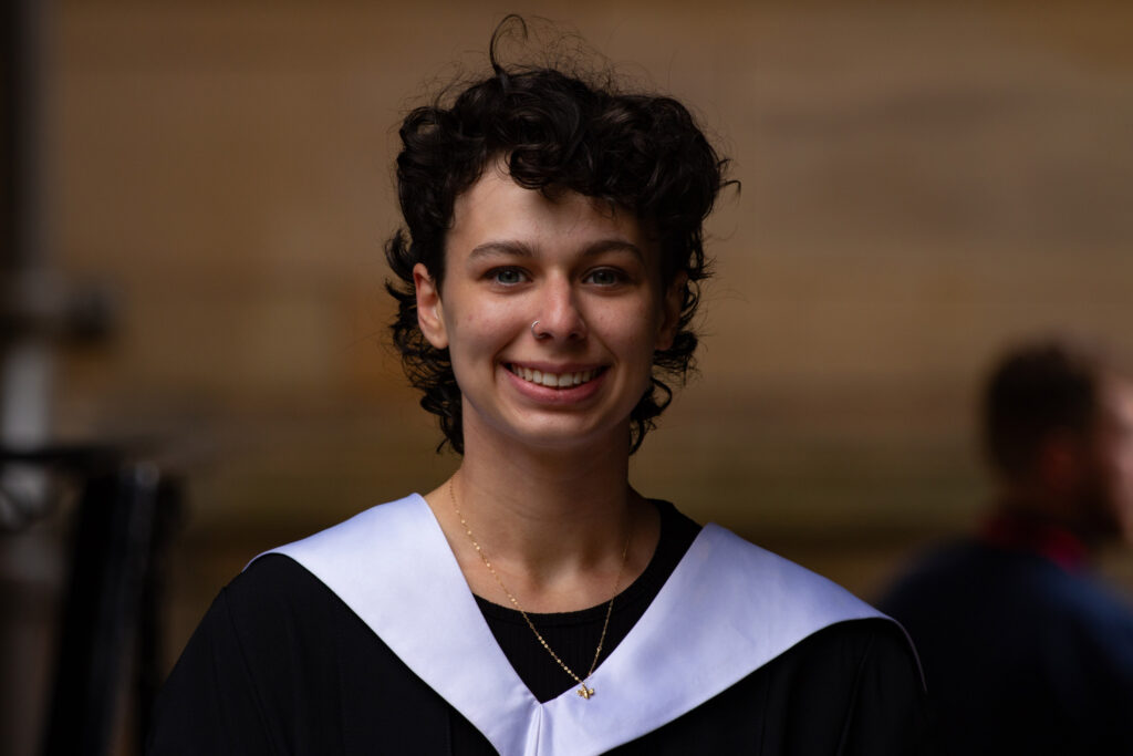 Close up portrait of a person smiling at their graduation ceremony.