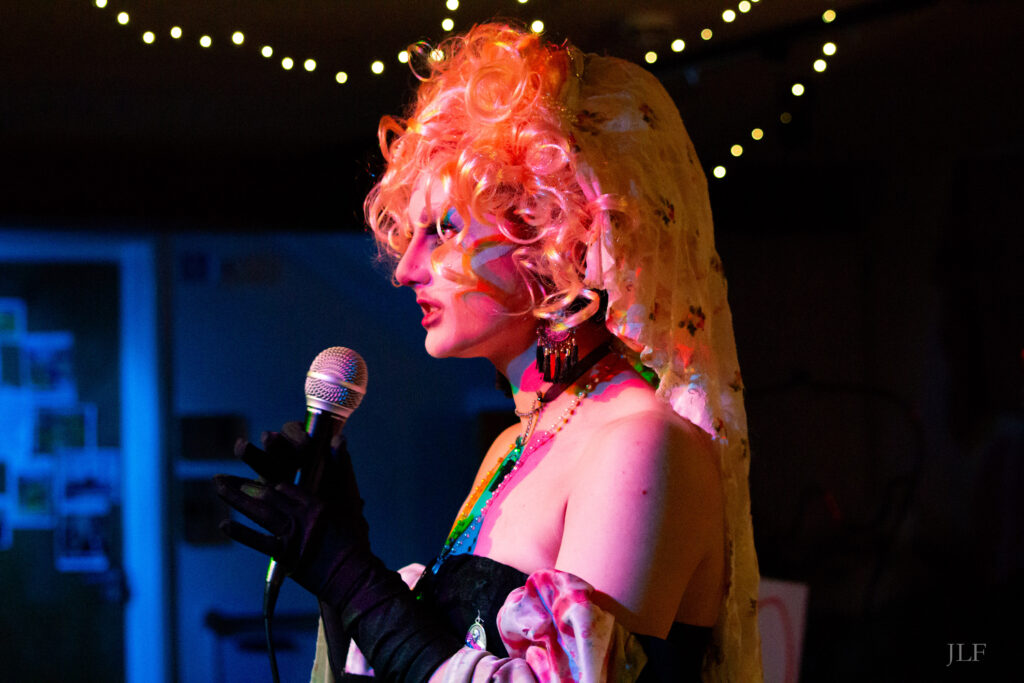 A drag performer singing in a microphone during a show.