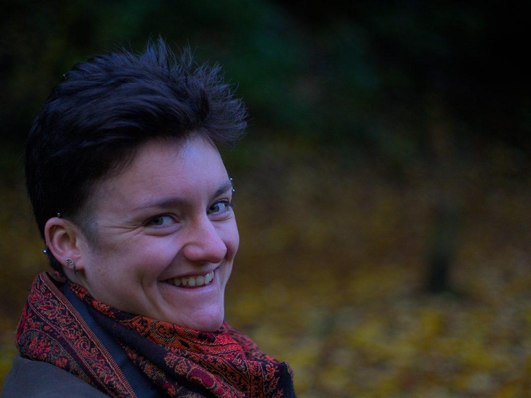 Portrait of Jules smiling on a wooden path, autumn colours, leaves on the ground.